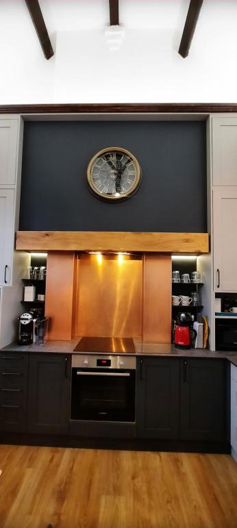 a large kitchen with a clock on the wall at The Old Schoolhouse in Whitstable