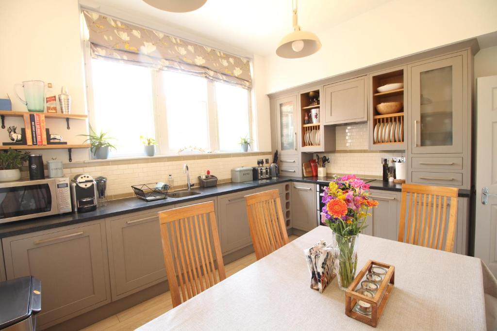 a kitchen with a table with a vase of flowers on it at The Old Schoolhouse in Whitstable