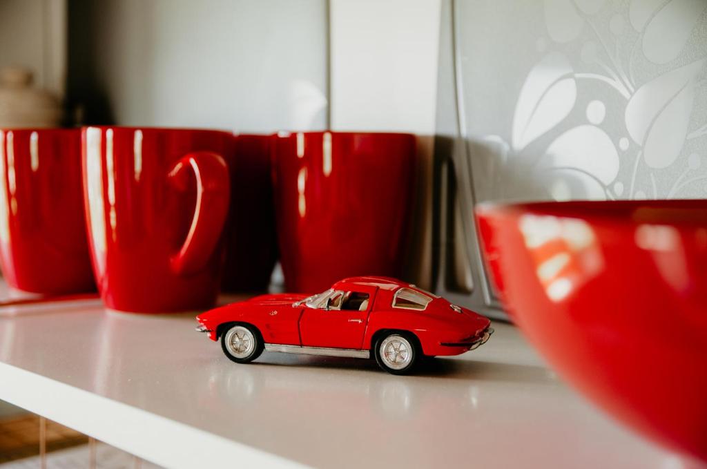 ein rotes Spielzeugauto auf einem Tisch neben roten Tassen in der Unterkunft KORCAL faházak in Koroncó