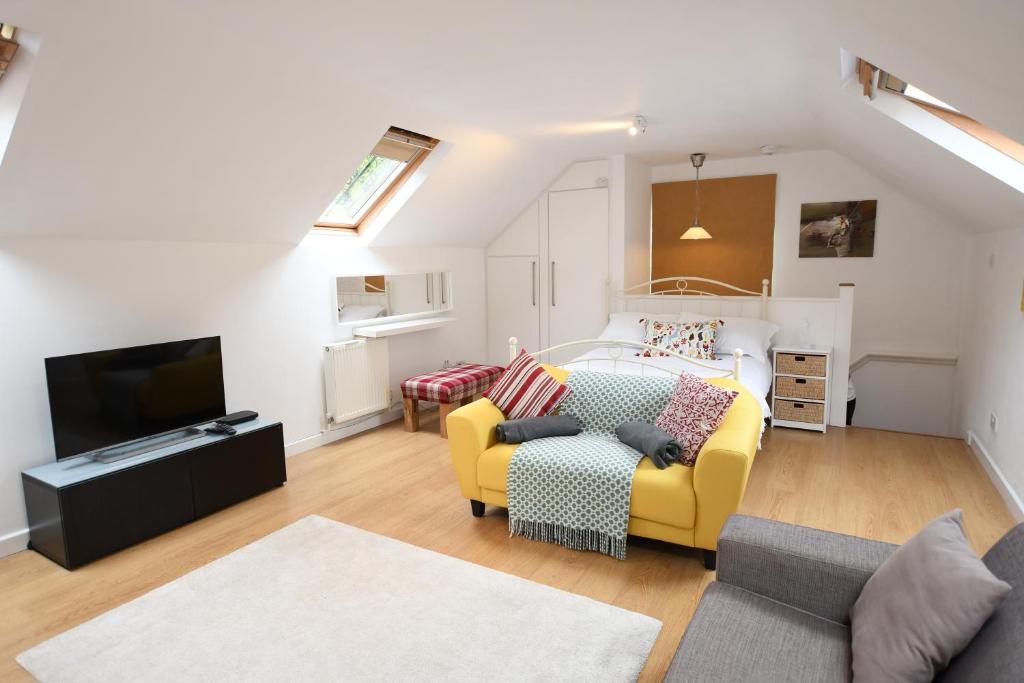 a living room with a yellow couch and a television at The Coach House Studio Apartment in Leamington Spa