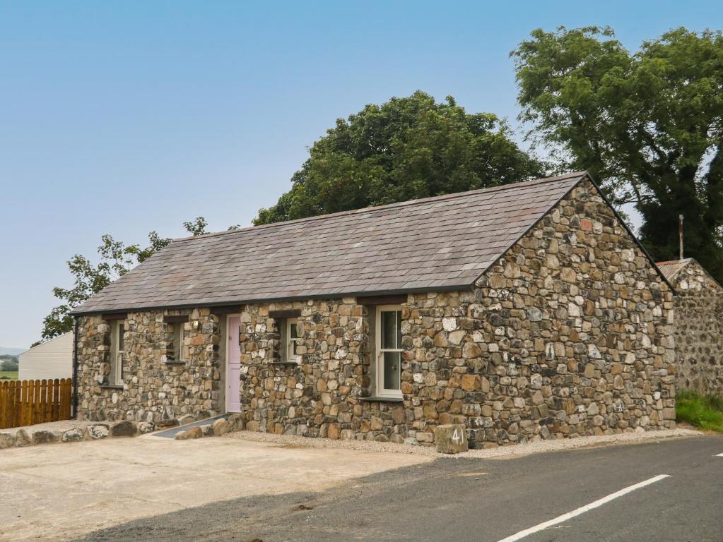 un edificio de piedra al lado de una carretera en Old Shop Cottage, en Limavady