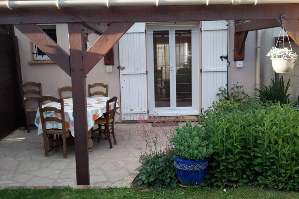 een patio met een tafel en stoelen en een huis bij Agréable logement dans petit village sud-essonne in Champcueil