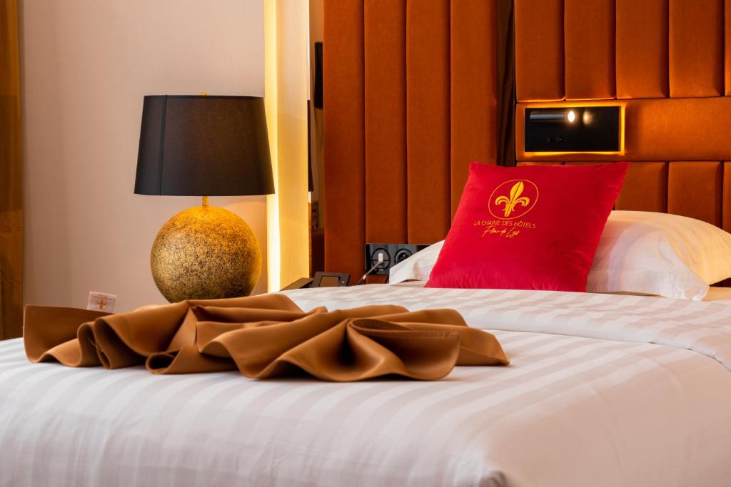 Hôtel Fleur de Lys Point E في داكار: غرفة فندق بسرير ومخدة حمراء