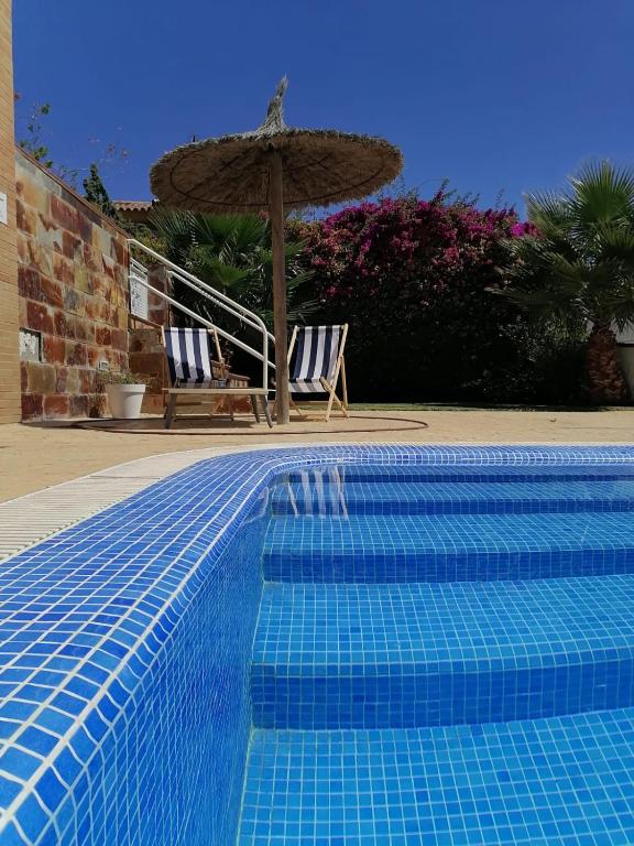 a swimming pool with two chairs and an umbrella at Hotel Marisma Sancti Petri in Chiclana de la Frontera