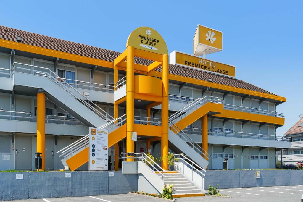 a hotel with a yellow building with stairs at Première Classe Villejust in Villejust