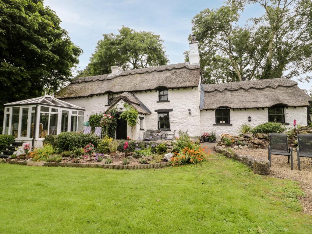 an old cottage with a garden in front of it at Tyn Y Graig in Moelfre