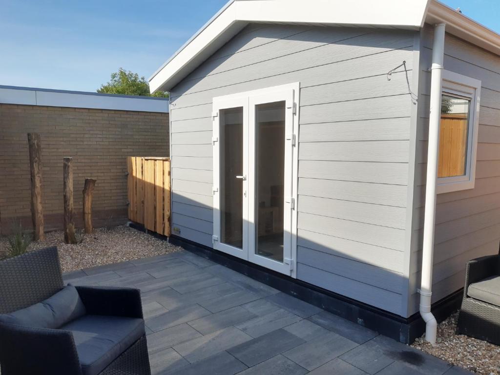 een kleine witte schuur met een patio bij Vakantiechalet "Huisje onder de Toren" in Oostkapelle