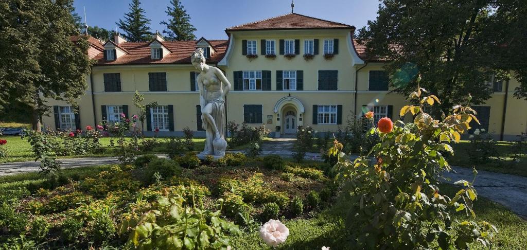 a house with a statue in a garden in front of it at VILA GOLF 22 in Rogaška Slatina