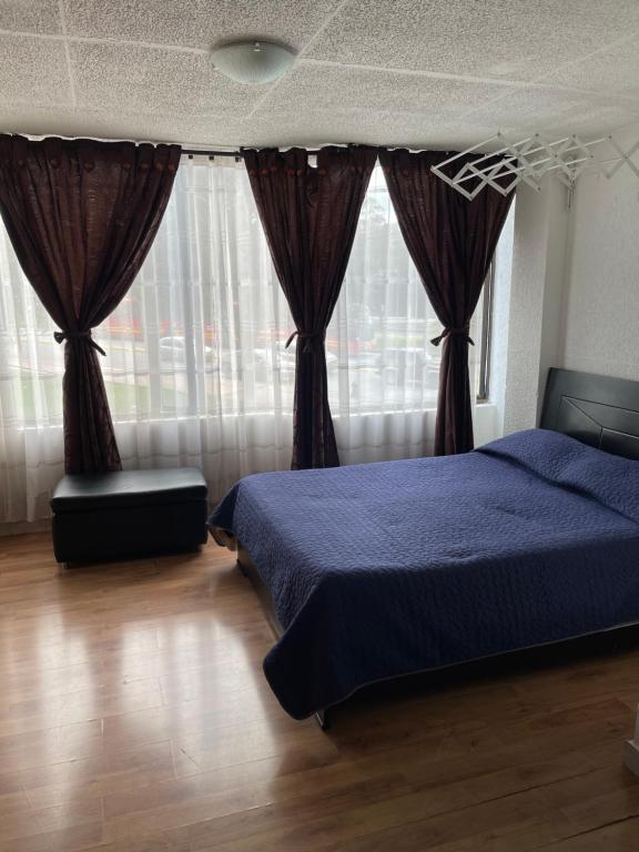 Schlafzimmer mit blauem Bett und Vorhängen in der Unterkunft Apt est castellana cll 97 in Bogotá