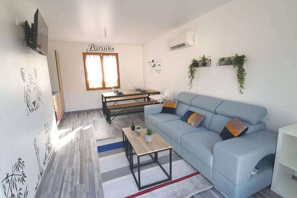 een woonkamer met een blauwe bank en een tafel bij Un petit coin de paradis1,proche beauval & châteaux in Meusnes