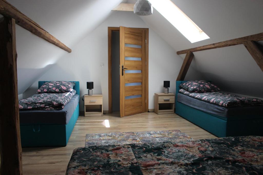 a attic room with two beds and a door at Domek Nieledwia in Milówka
