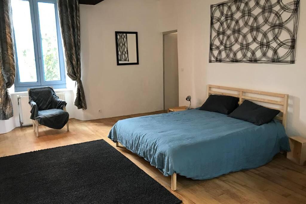 1 dormitorio con 1 cama azul y 1 silla en Studio et terrasse au sein d'un manoir XVIIème en Montauban-de-Bretagne
