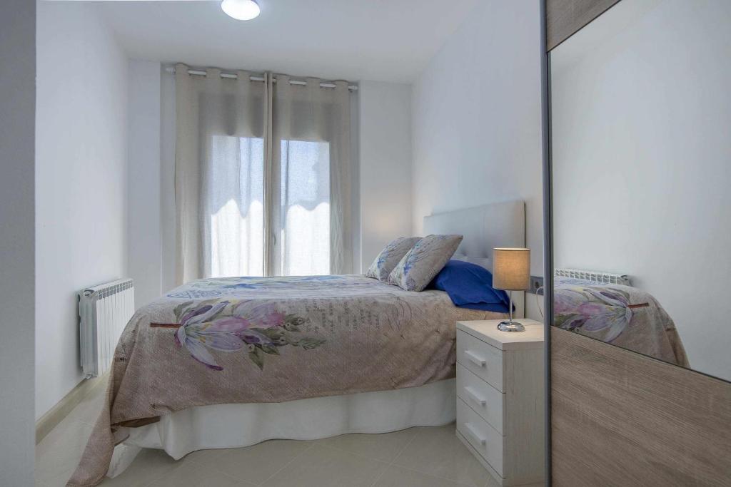 a white bedroom with a bed and a mirror at Apartamento centro histórico en Manresa in Manresa