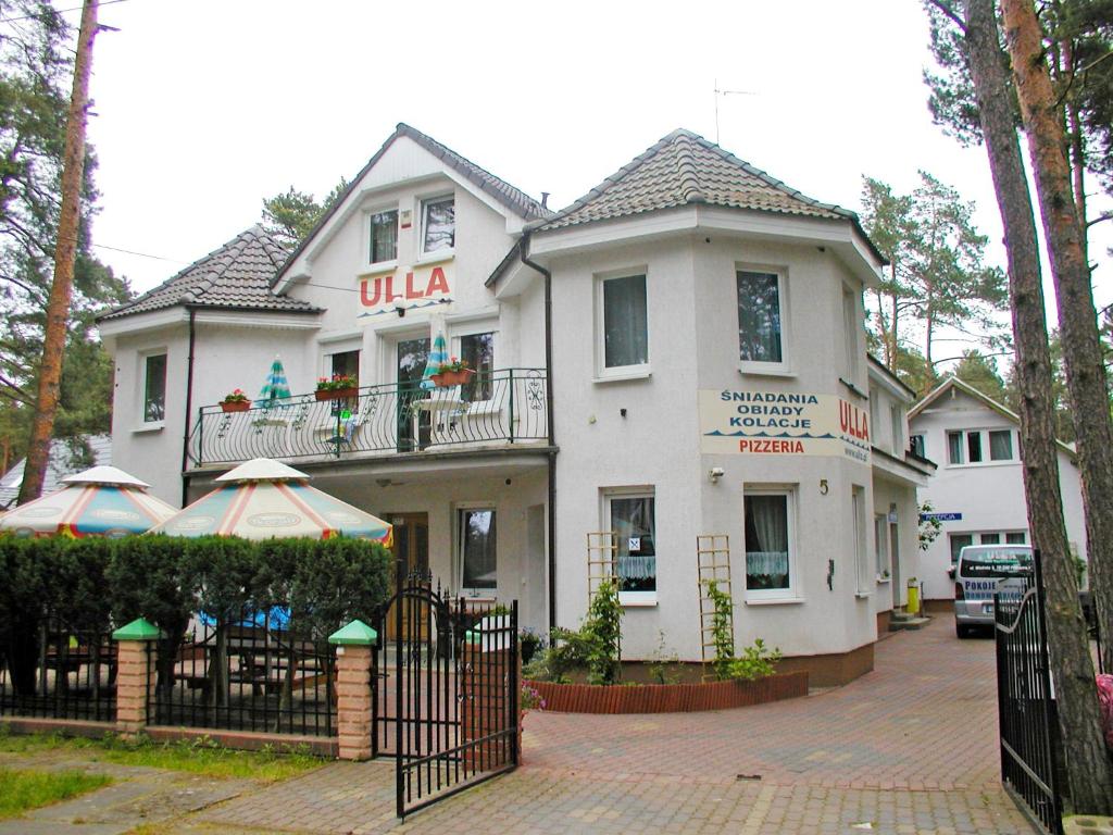 a white house with a gate in front of it at Pension Dom Wypoczynkowy Ulla in Pobierowo