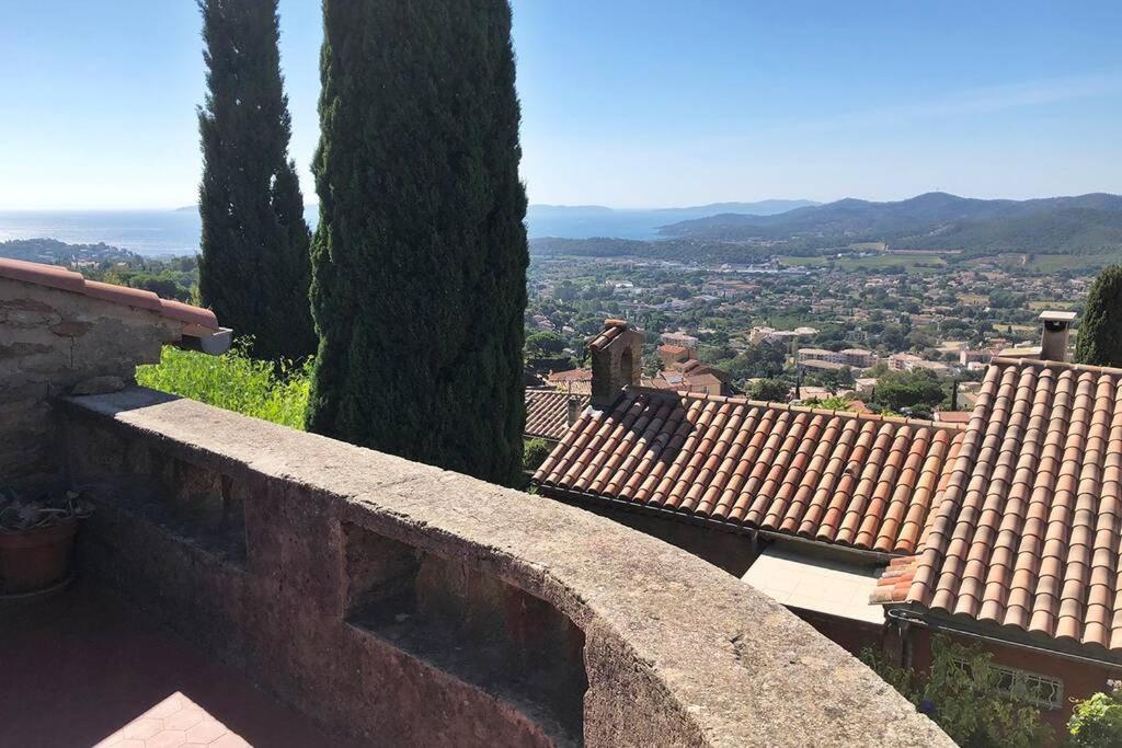 a stone wall with trees and a view of a city at Magnifique maison de village clim vue mer 6 pers in Bormes-les-Mimosas