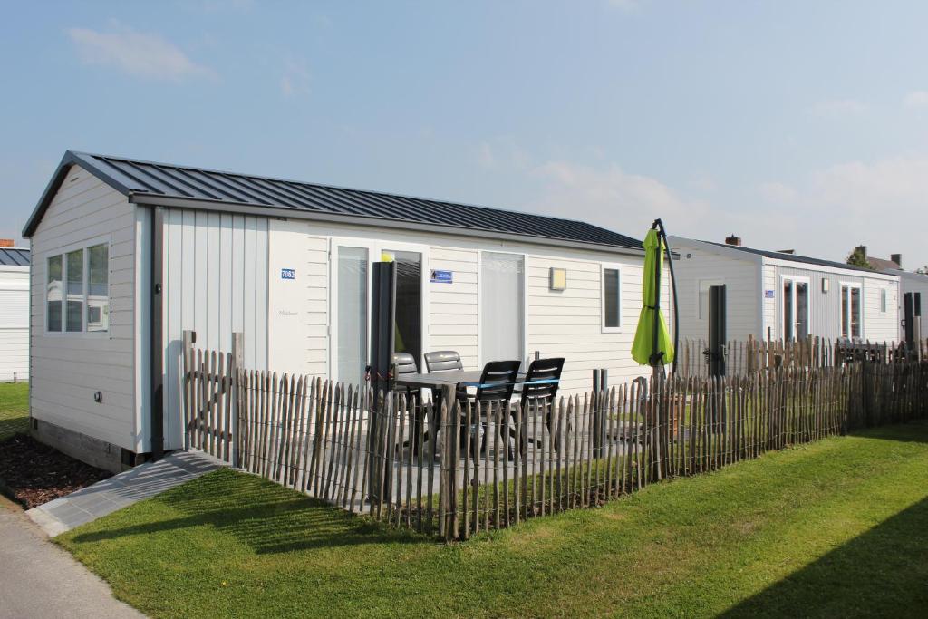 a white building with a table and chairs and a fence at Familie-Vakantiehuisje aan Zee (Knokke-Heist) in Knokke-Heist