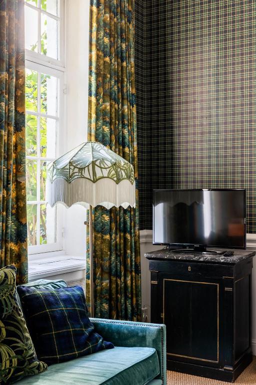a living room with a couch and a television at Molenmeers Boutique Guesthouses in Bruges
