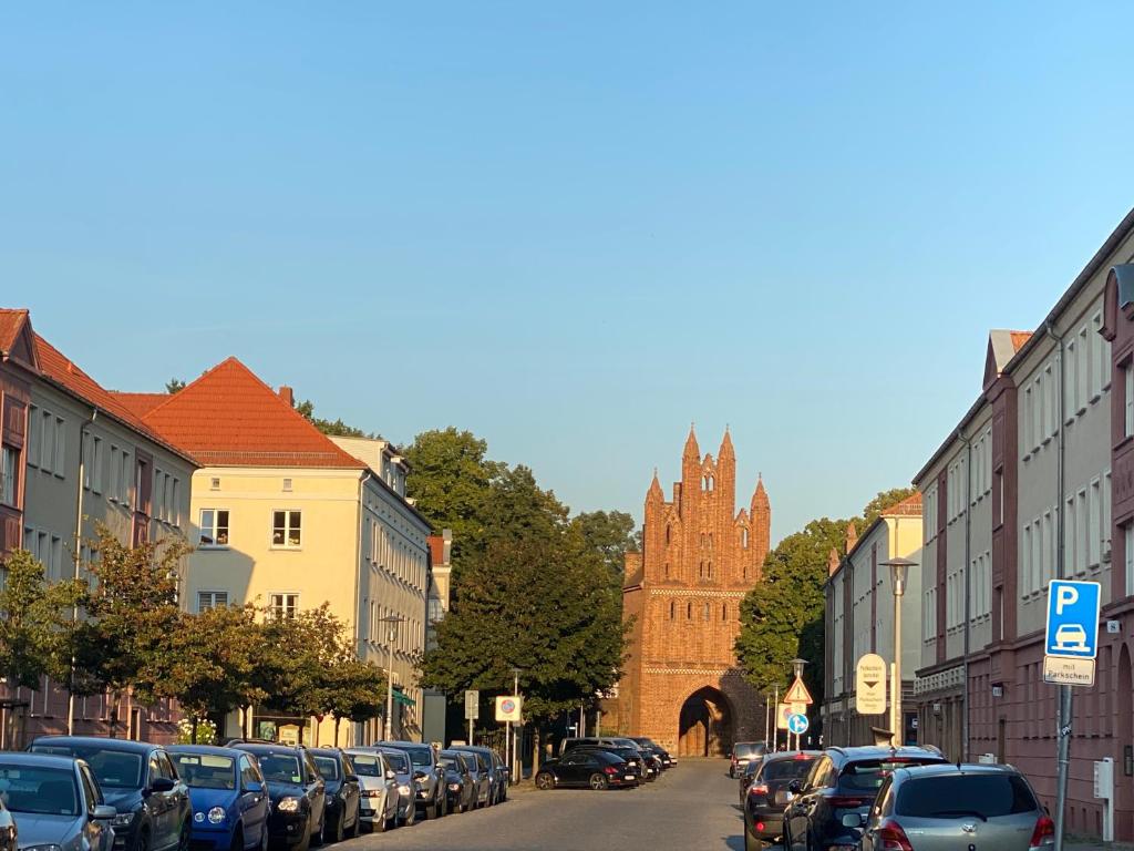 een stadsstraat met geparkeerde auto's en een kerk bij Mitten im Herzen von Neubrandenburg in Neubrandenburg
