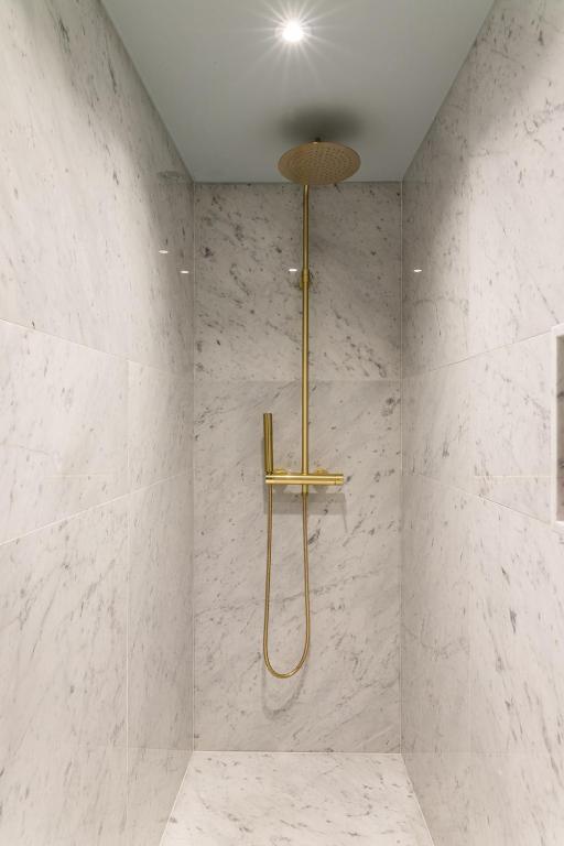 a bathroom with a shower with white marble walls at Molenmeers Boutique Guesthouses in Bruges