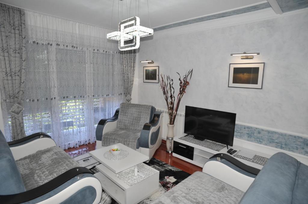a living room with a couch and a desk with a computer at Twins Apartments in Čačak