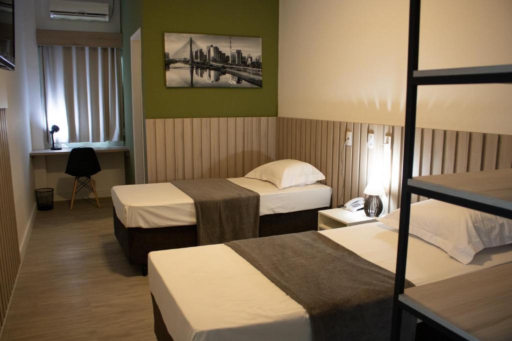 a hotel room with two beds and a window at Hotel Jardim Sul in São José dos Campos