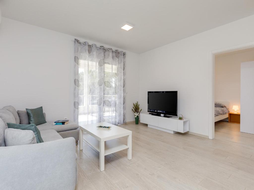 a white living room with a couch and a tv at Apartment Aria in Poreč