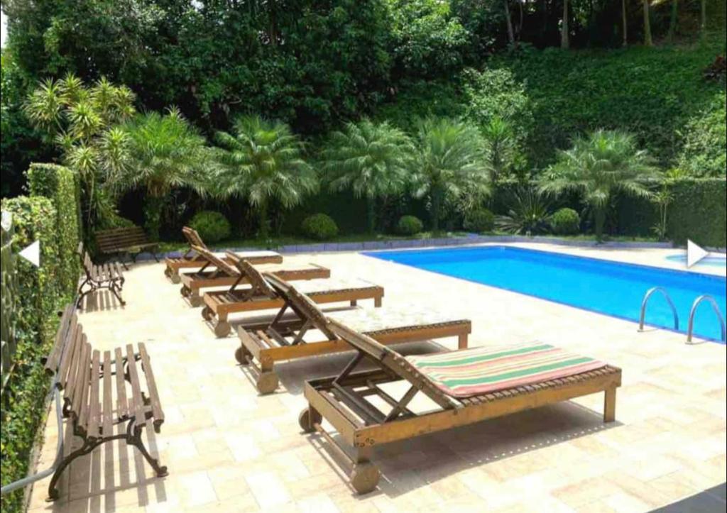 a row of lounge chairs next to a swimming pool at Chácara espaçosa e aconchegante em Juquitiba Sp in Juquitiba