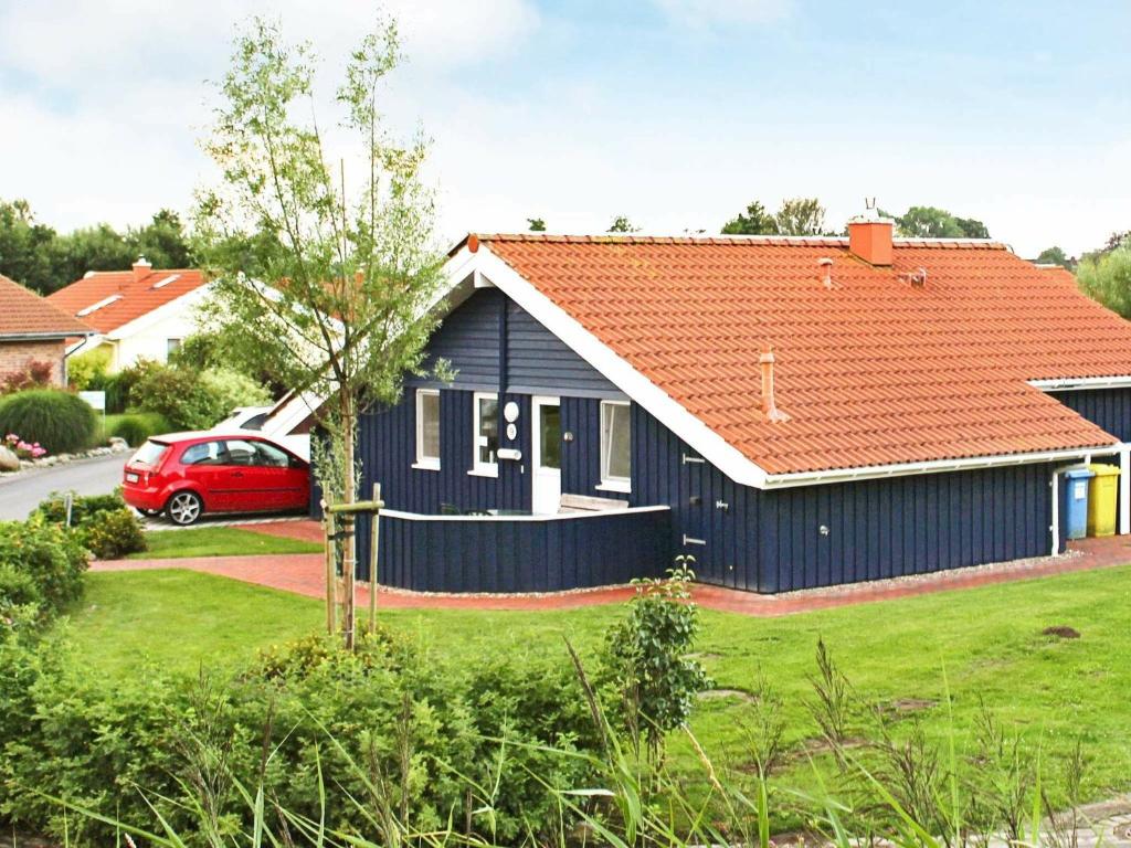 ein blaues Haus mit orangefarbenem Dach in der Unterkunft 6 person holiday home in Otterndorf in Otterndorf