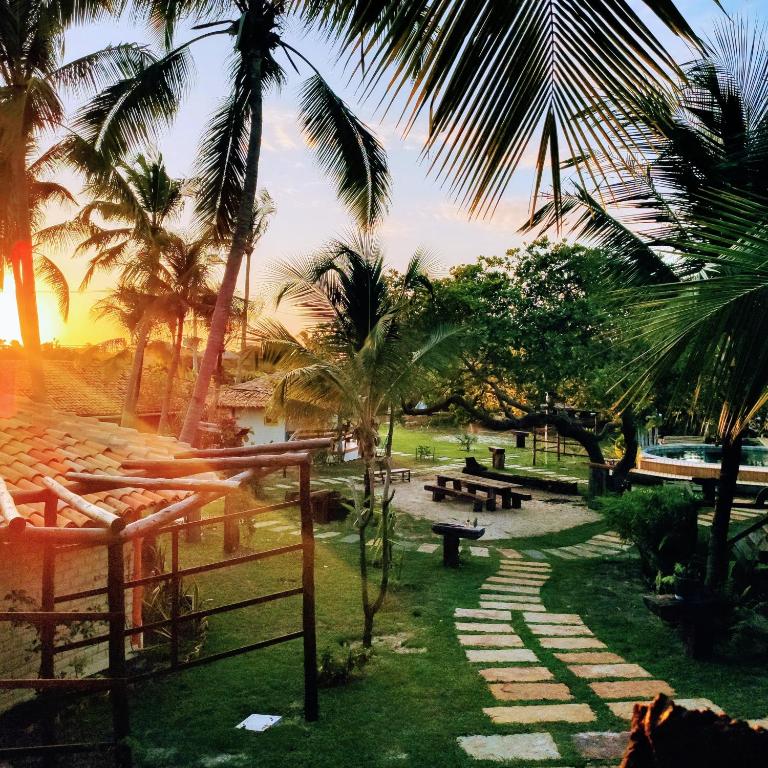 a park with palm trees and benches and a sunset at Convento Arcádia in Atins