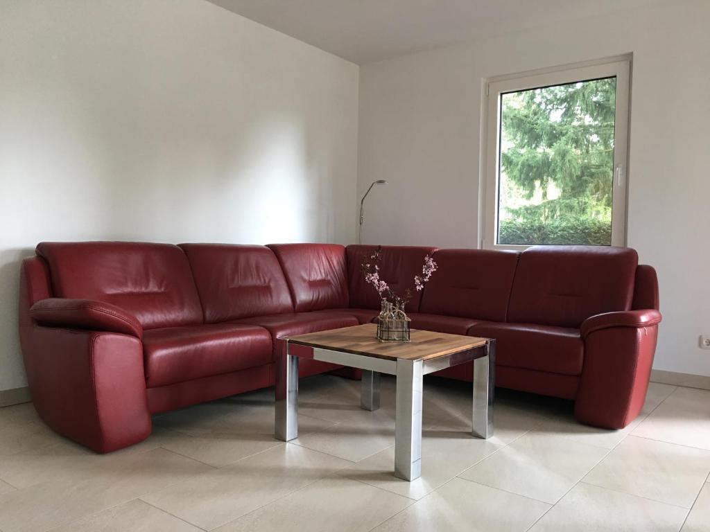 un sofá rojo en una sala de estar con mesa en FERIENHAUS POTSDAM BERLIN GÄSTEHAUS MONTEURZIMMER SEENÄHE, en Potsdam