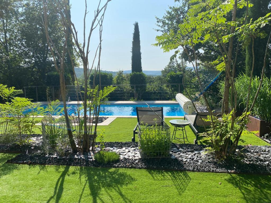 um jardim com duas cadeiras e uma piscina em La Ronde des Bois - Romance et Bien Être - Jacuzzi privatif-piscine-patio em Mellecey