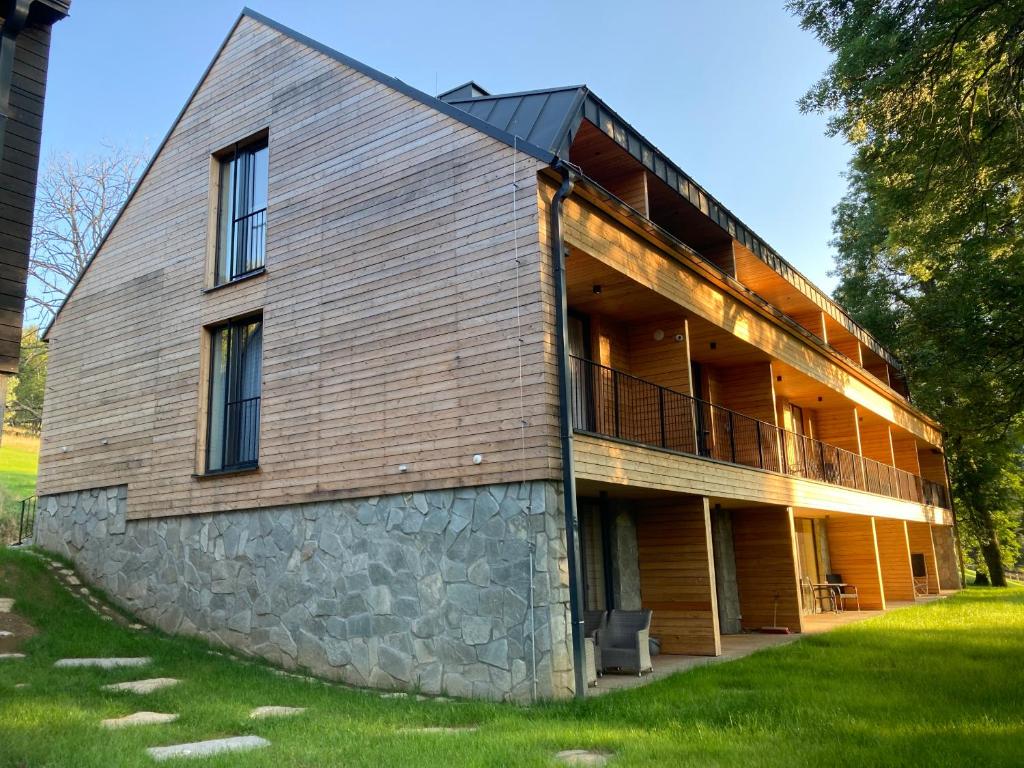 ein großes Holzgebäude mit einer Steinmauer in der Unterkunft Apartmán U Kola na Brčálníku in Hojsova Stráž