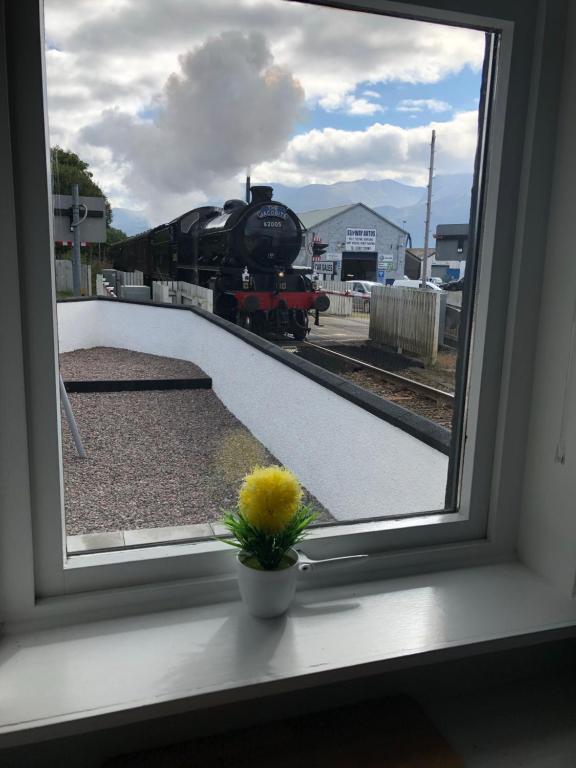 a window with a view of a train on the tracks at Annat Cottage in Corpach