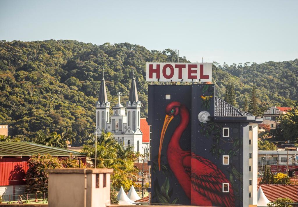 una señal de hotel con un pájaro pintado en un lateral de un edificio en Andardac Hotel, en Guaramirim