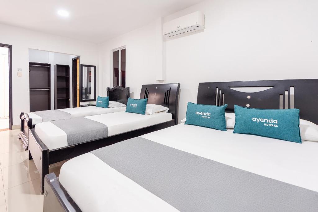 três camas num quarto com almofadas azuis em Ayenda Union em Valledupar