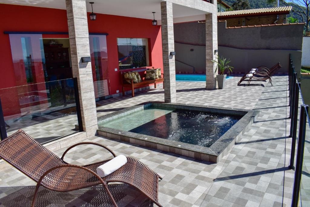 a swimming pool on a patio with chairs and a house at Pousada Vista Dell Mar in Ubatuba