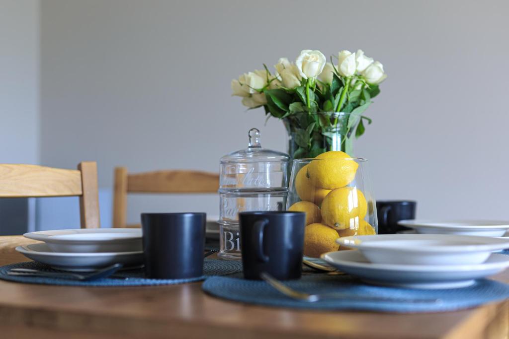 una mesa con platos y tazas y un jarrón de flores en Sea Zone Climatic apartament by the bay en Puck
