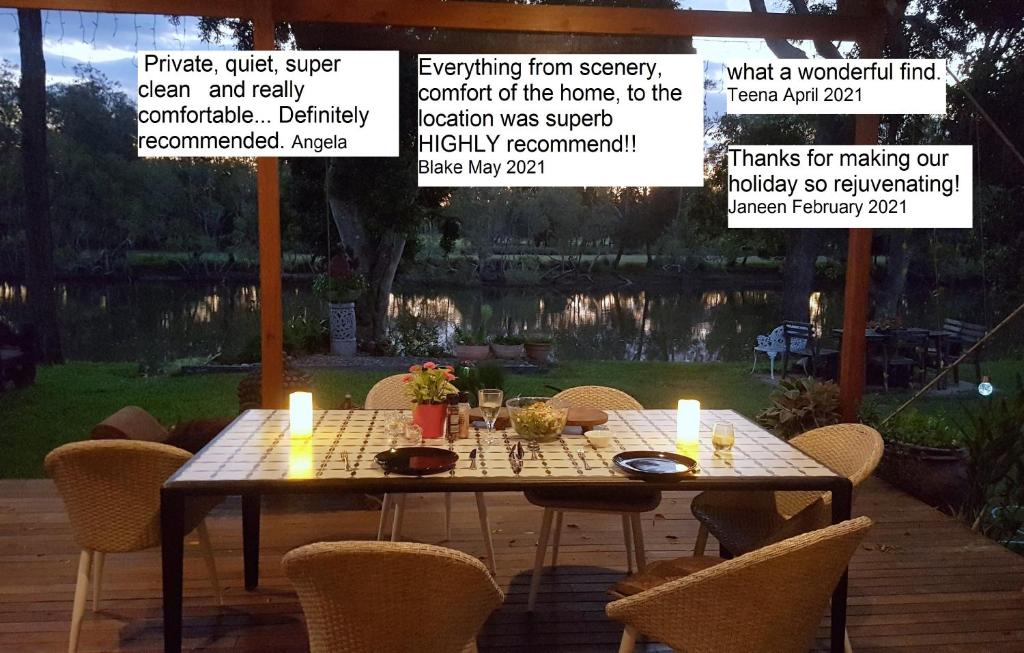 a wooden table with candles on top of a patio at Januce - delightful river front house in Urunga in Urunga