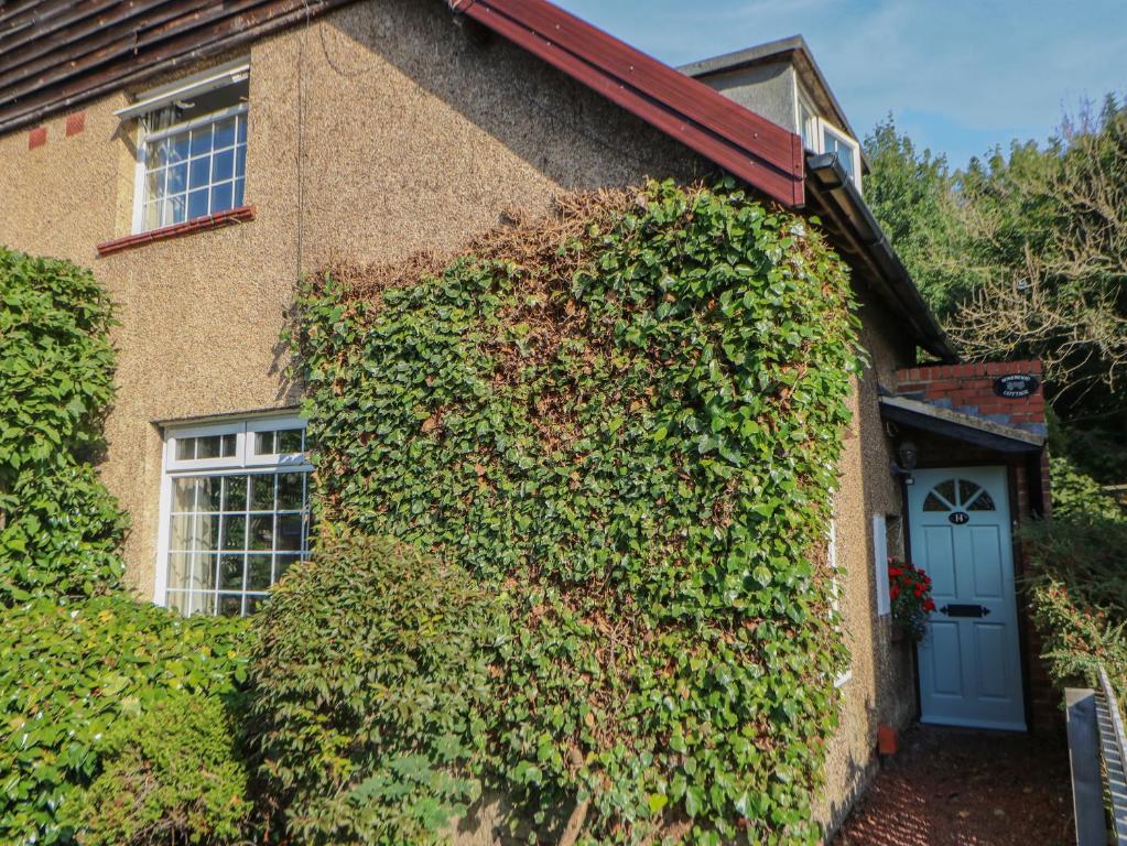 uma casa coberta de hera com uma porta azul e janelas em Rosewood Cottage em Durham