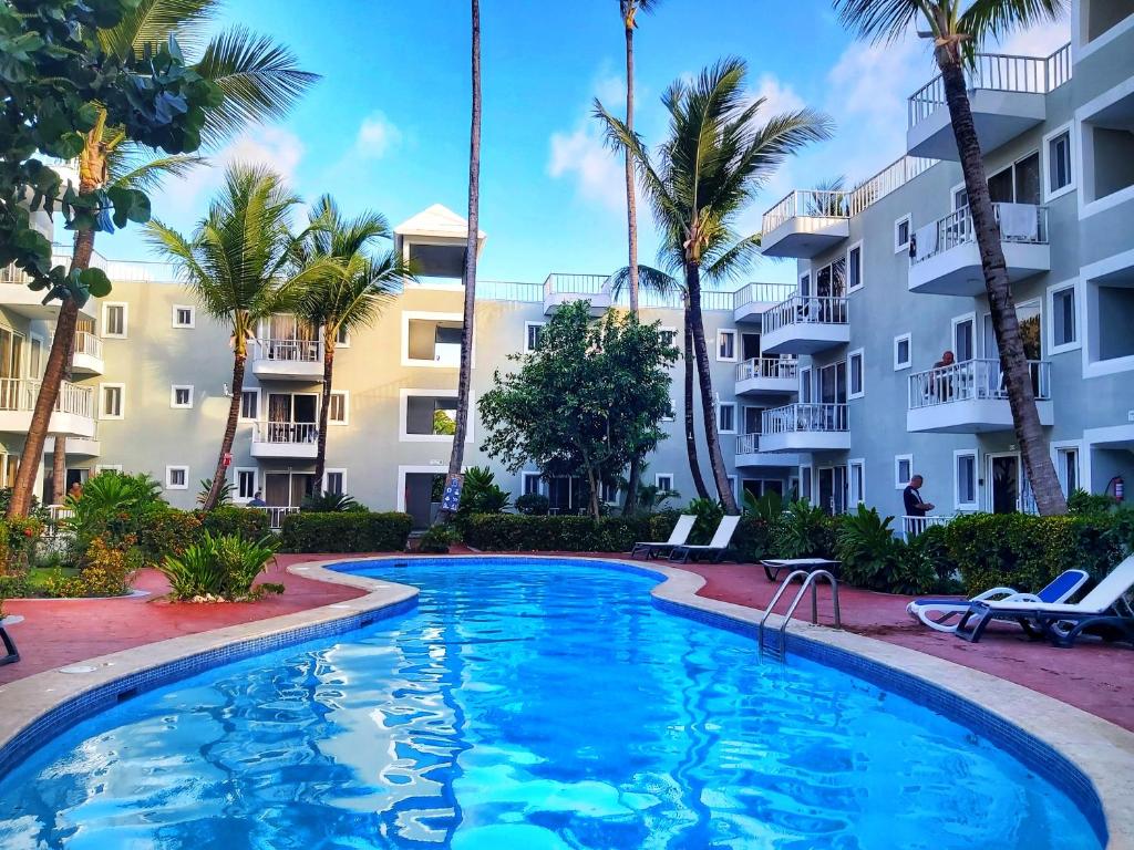 ein Swimmingpool vor einem Gebäude mit Palmen in der Unterkunft RELAX STUDIES DELUXE SOL CARIBE in Punta Cana