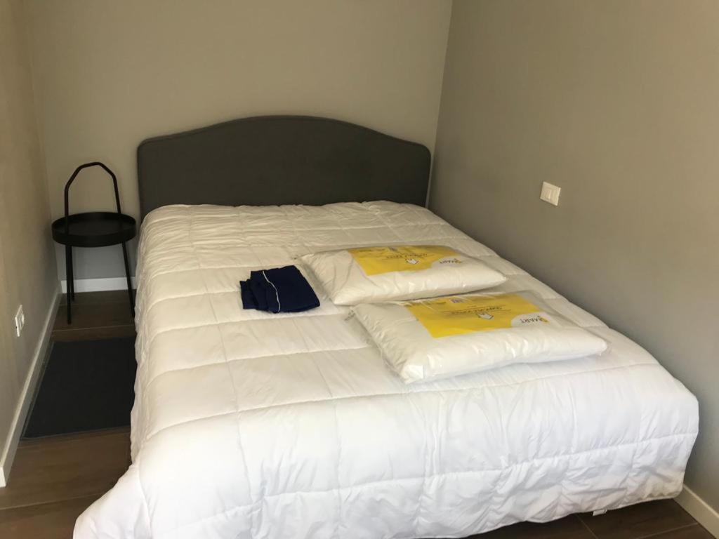 a bed with white sheets and yellow pillows on it at White House 4 in Brescia