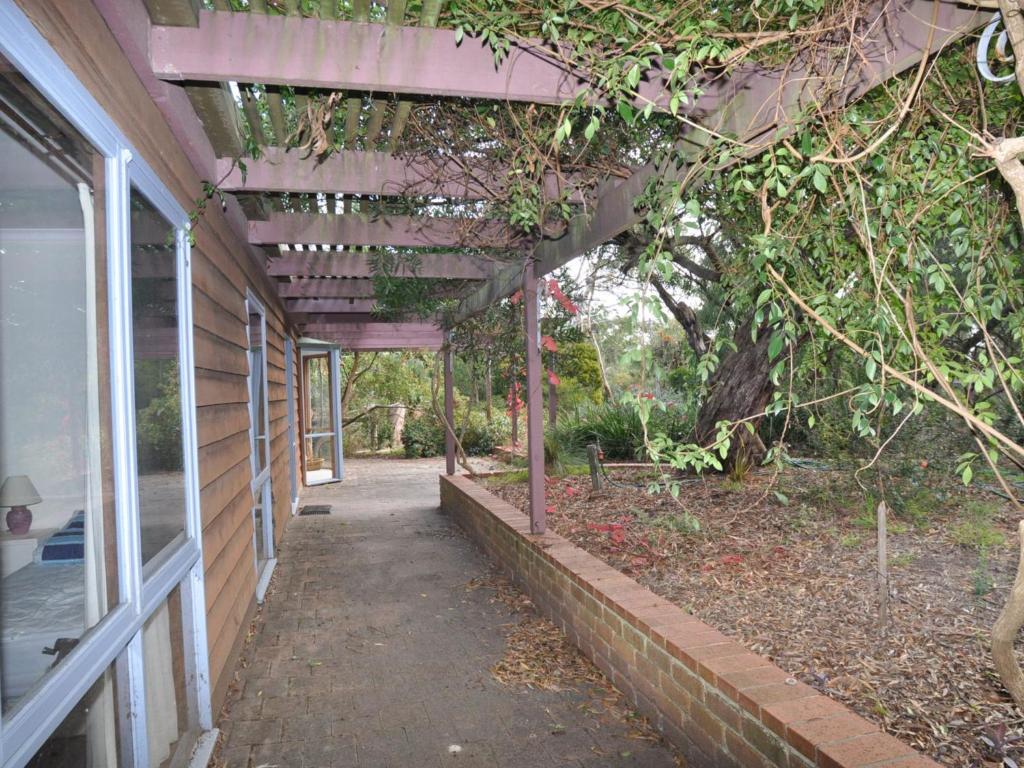 een lege loopbrug naast een gebouw met een boom bij Beechwood Surf Side in Inverloch