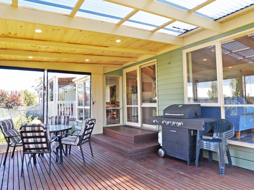 a screened porch with a grill and a table and chairs at Archies Beachside Abode - Pet Friendly Outside Only in Inverloch