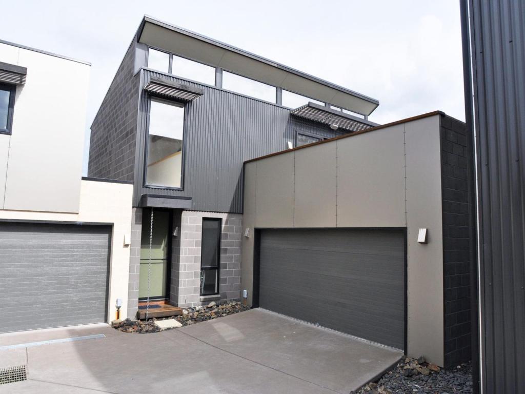 a black house with two garage doors at Luxe Townhouse 2 Inlet Side Wifi in Inverloch