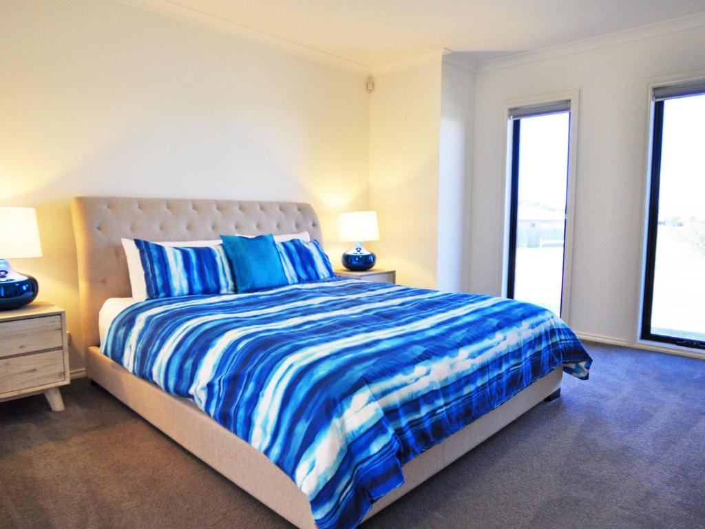 a bedroom with a bed with blue and white sheets at Plovers Rest in Inverloch