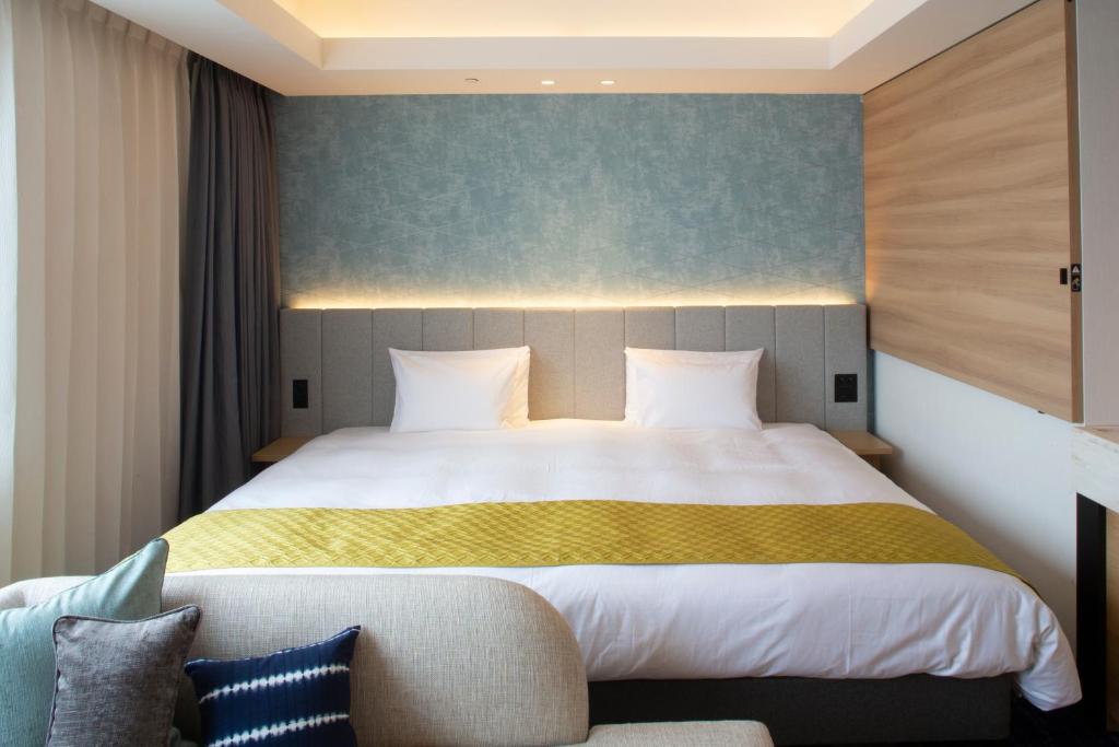 a bedroom with a large bed and a couch at Nikko Style Nagoya in Nagoya