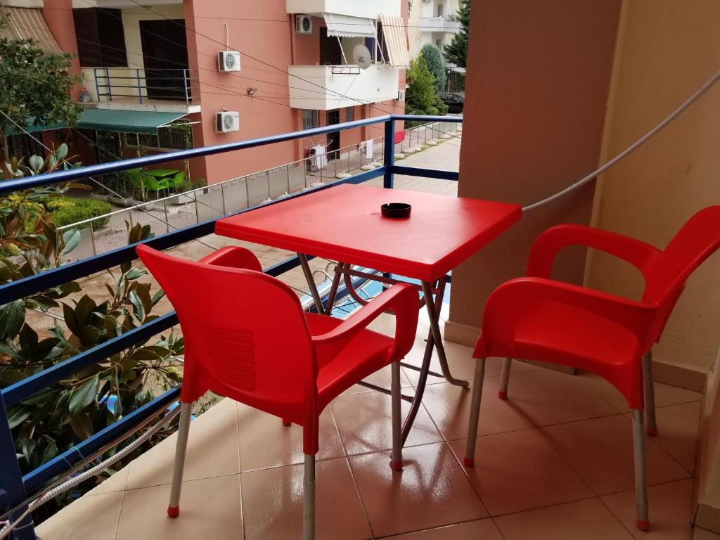 uma mesa vermelha e cadeiras numa varanda em Apartament Emiri Golem em Golem