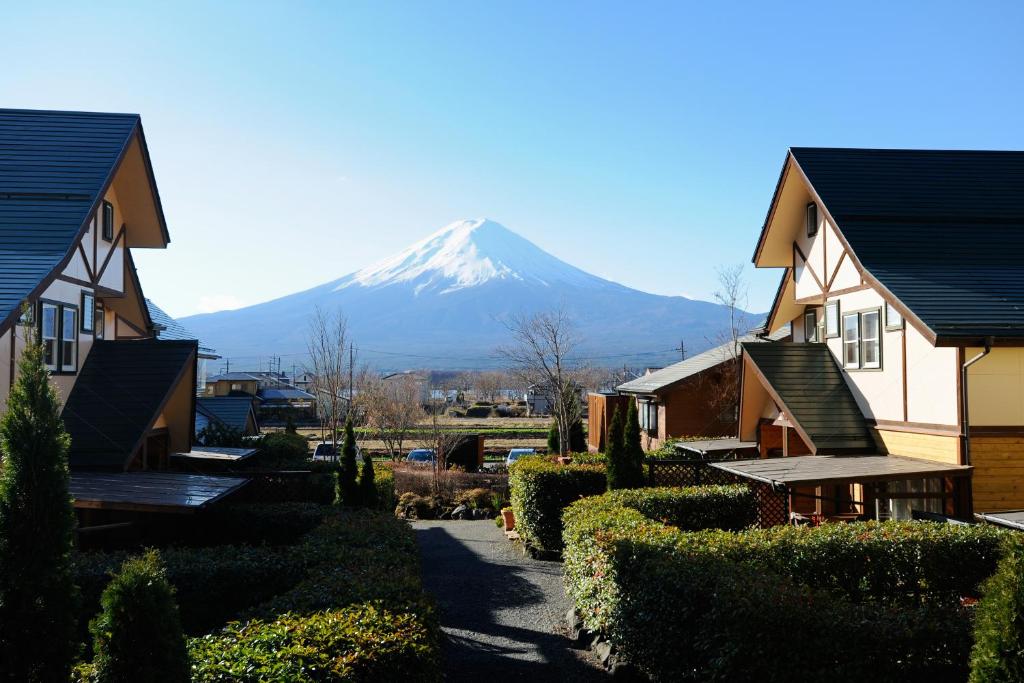 una montaña cubierta de nieve en la distancia detrás de las casas en Lake Villa Kawaguchiko, en Fujikawaguchiko