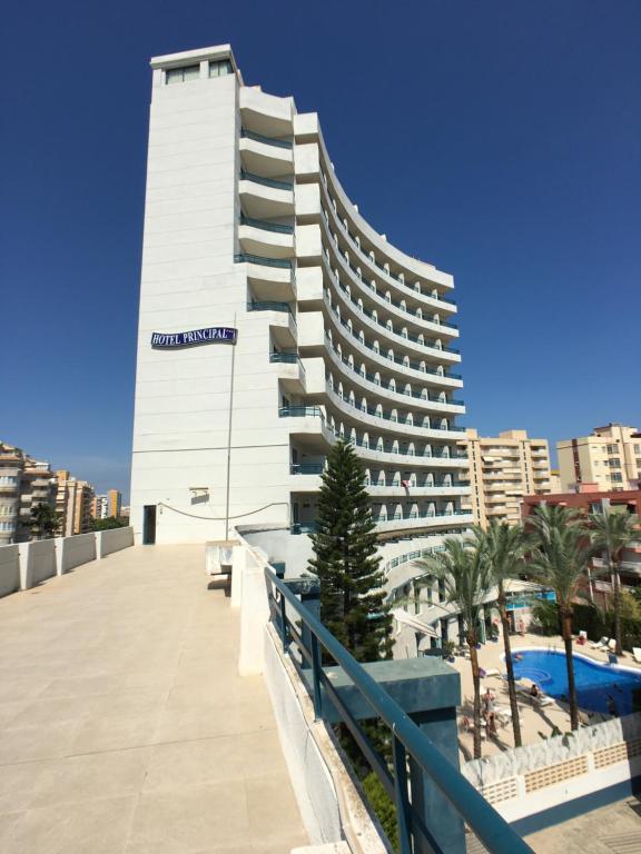 - un grand bâtiment blanc avec une piscine en face dans l'établissement Hotel Principal afiliado a RH, à Gandía