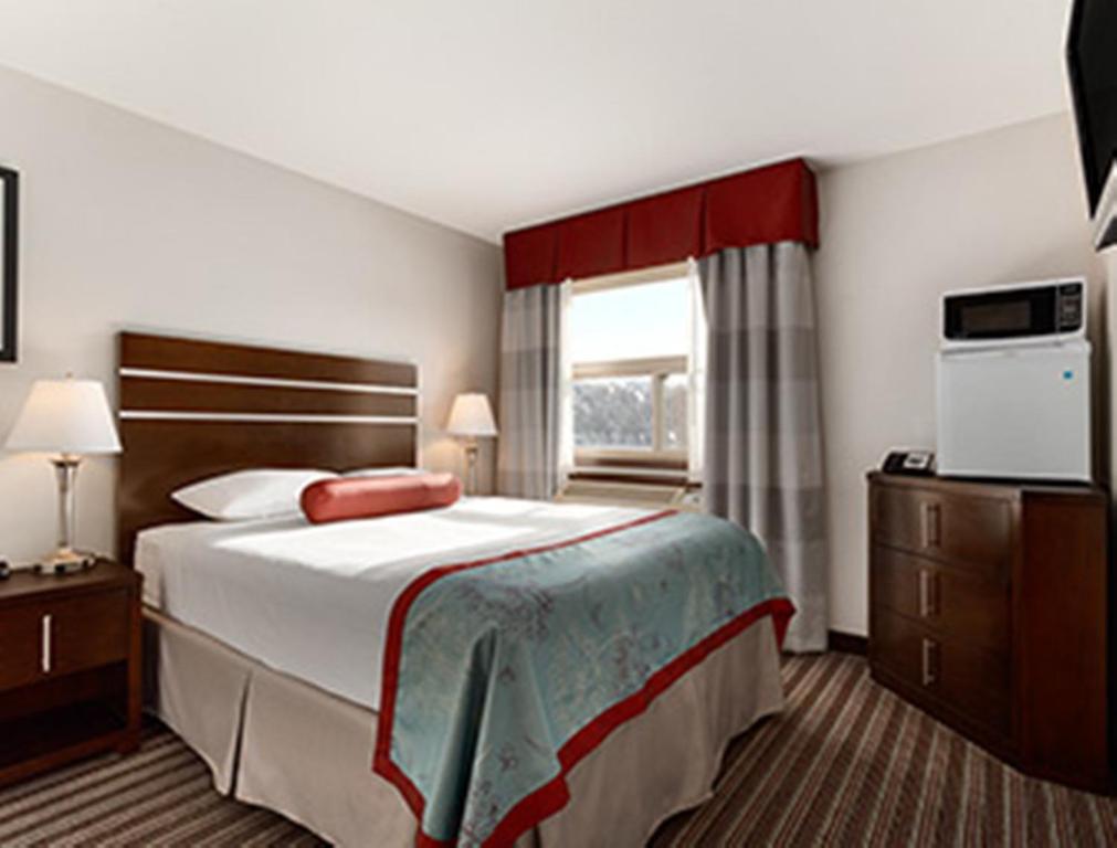a hotel room with a large bed and a window at Super 8 by Wyndham Saskatoon Near Downtown in Saskatoon